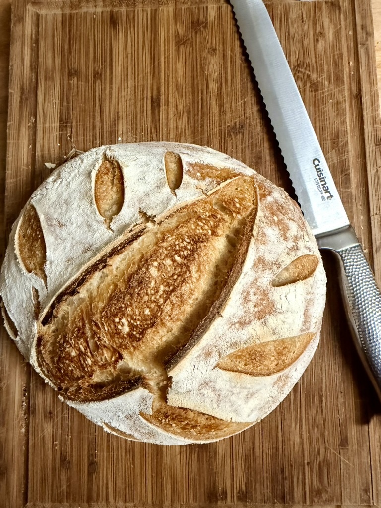 Decoratively scored artisan sourdough loaf on a wooden board