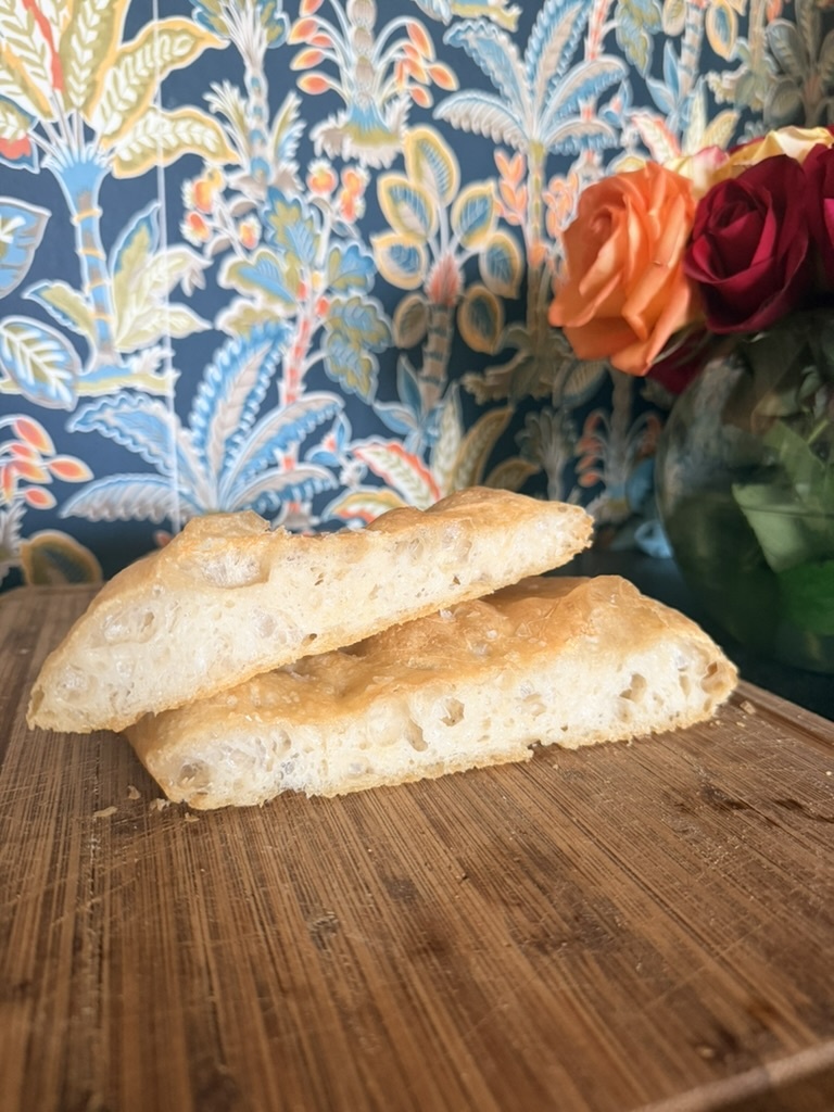 Golden focaccia slices arranged beside fresh flowers