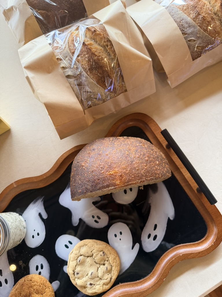 Packaged artisan loaves and fresh cookies arranged on a playful ghost serving tray